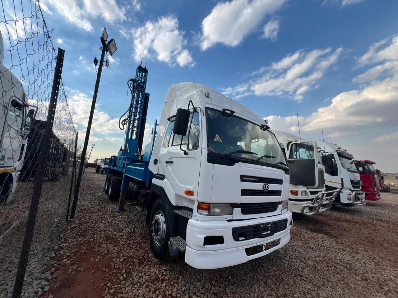 A row of used white semi-trucks at an auction yard.